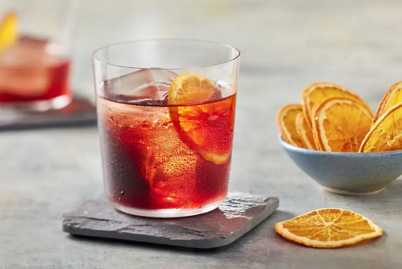 Klasyczny negroni przepis: orzeźwiający drink z ginem, Campari i wermutem, ozdobiony plasterkiem pomarańczy. Idealny na letnie wieczory.