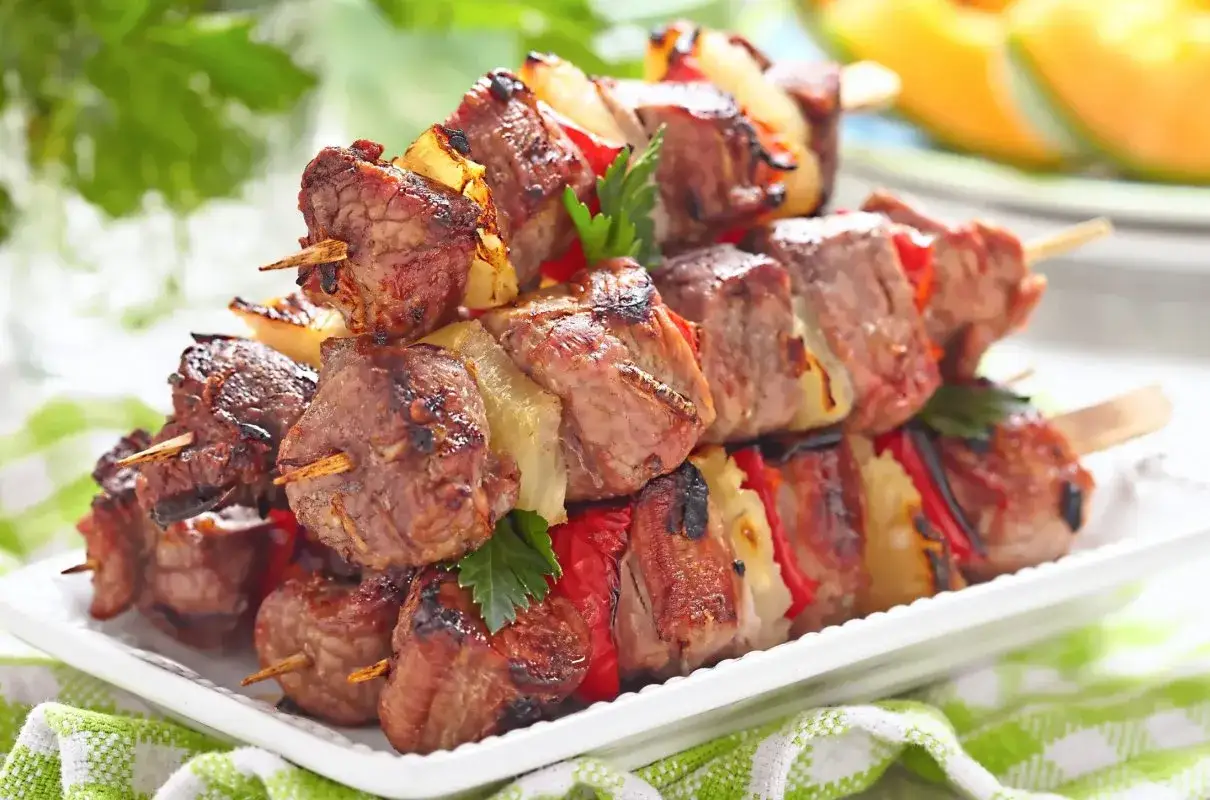 Szaszłyki z karkówki z papryką i cebulą, grillowane do perfekcji, podane na białym talerzu.