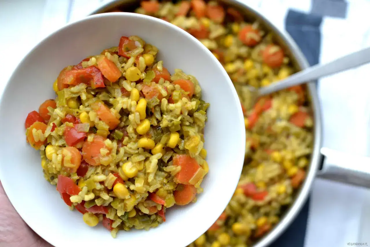 Aromaticzny ryż z curry, z marchewką, kukurydzą i papryką, podany w białej miseczce.