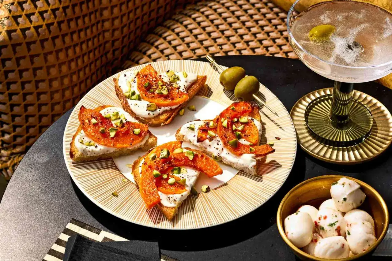 Lekkostrawny obiad: tost z serkiem, pomarańczą i pistacjami. Obok oliwki, drink i mini mozzarelle.