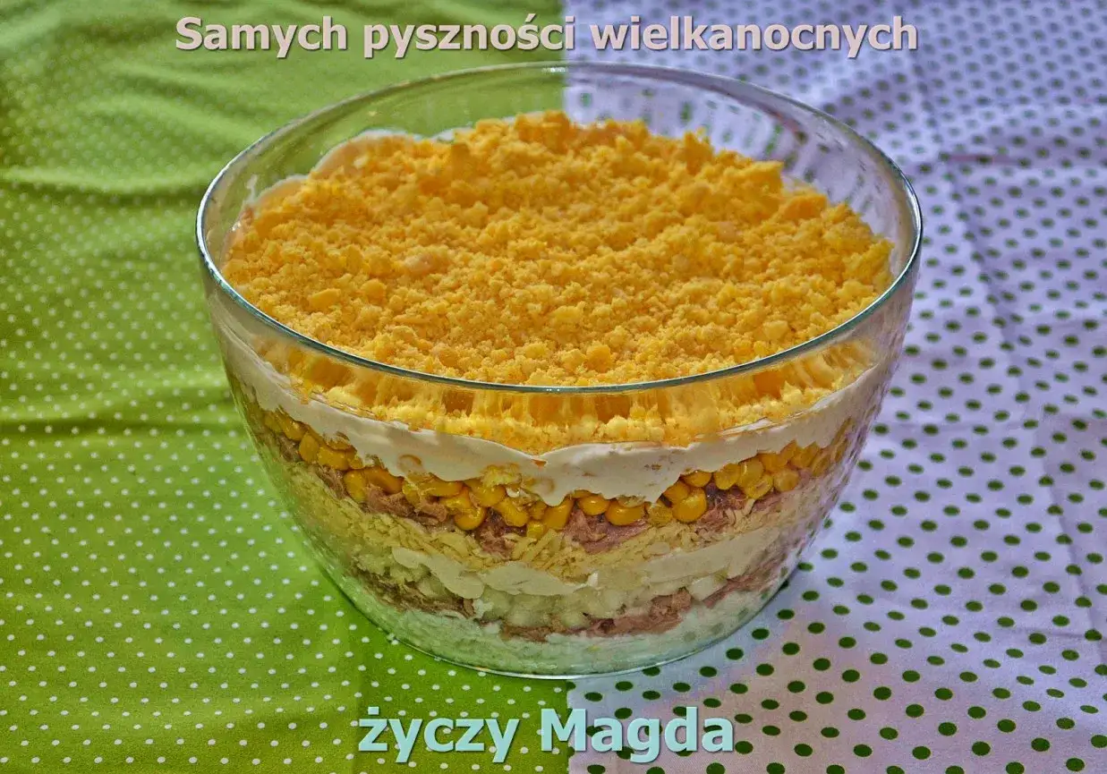 Warstwowa sałatka z tuńczykiem, kukurydzą i serem żółtym, udekorowana na wierzchu startym żółtkiem. Pyszna propozycja na Wielkanoc.