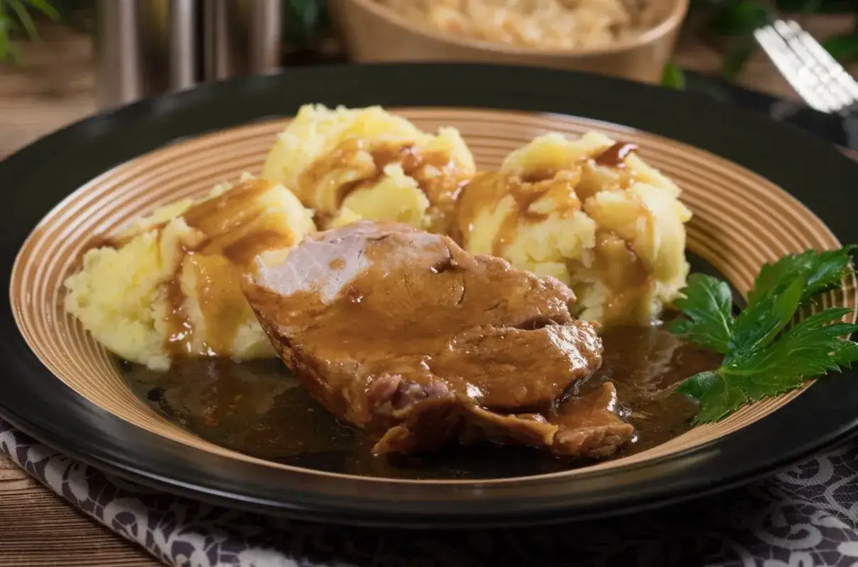 Mięciutka karkówka w sosie, podana z purée ziemniaczanym i listkiem pietruszki. Pyszny obiad gotowy!
