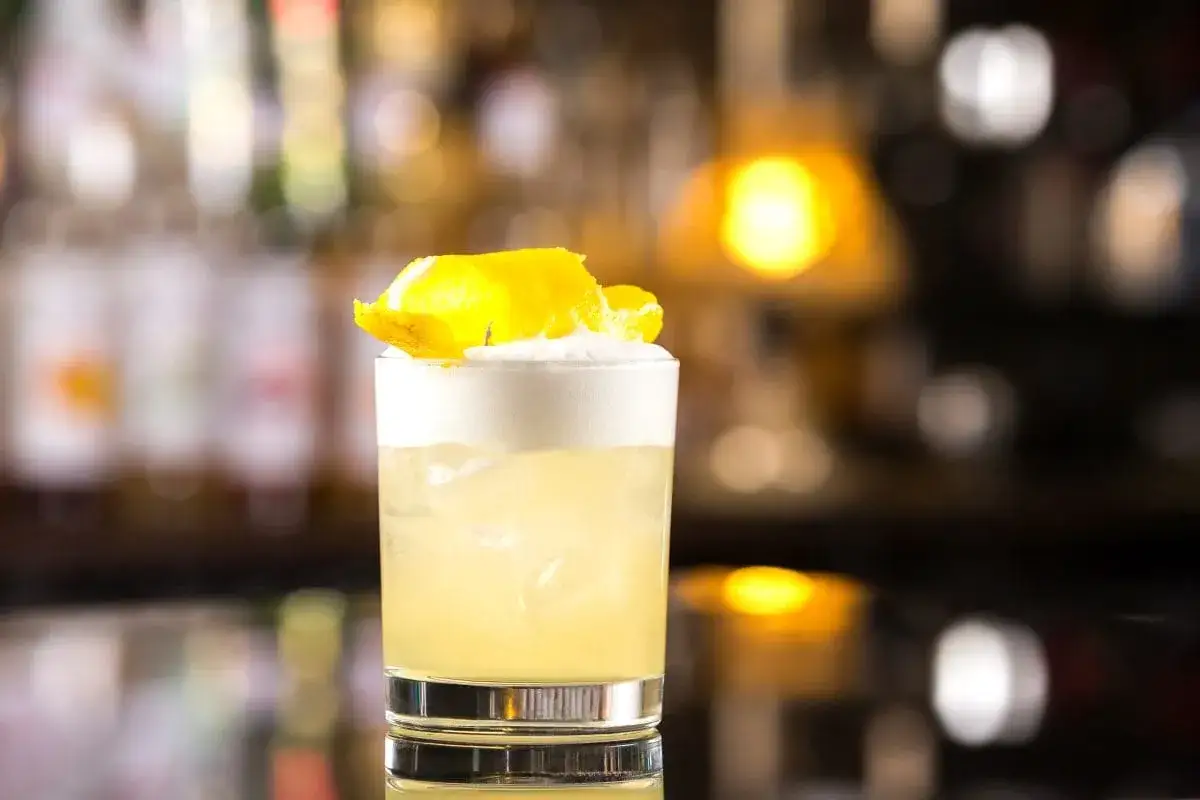 Klasyczny whisky sour przepis: orzeźwiający koktajl z pianką i skórką cytryny.