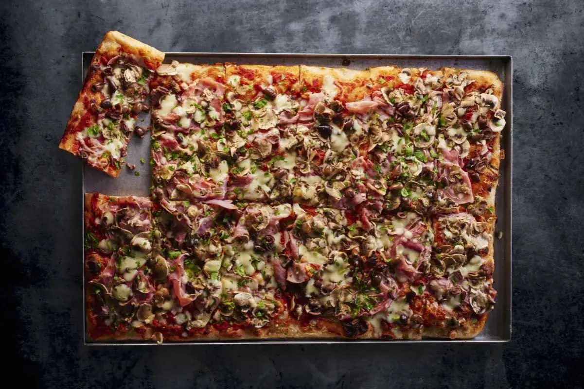 Najlepsza pizza domowa na dużą blachę, obficie posypana pieczarkami, szynką i oliwkami. Idealna na rodzinne spotkanie.