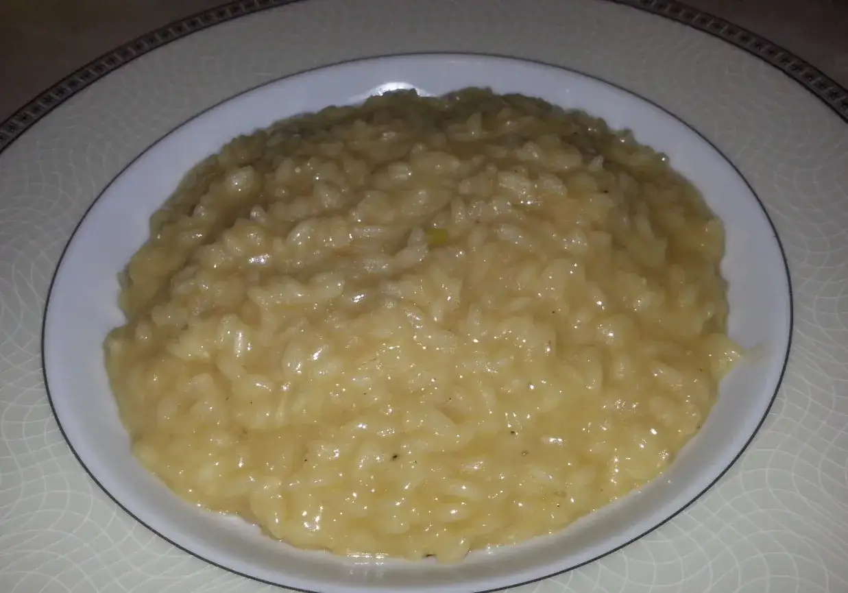 Kremowe risotto alla milanese, pachnące szafranem, podane na białym talerzu.