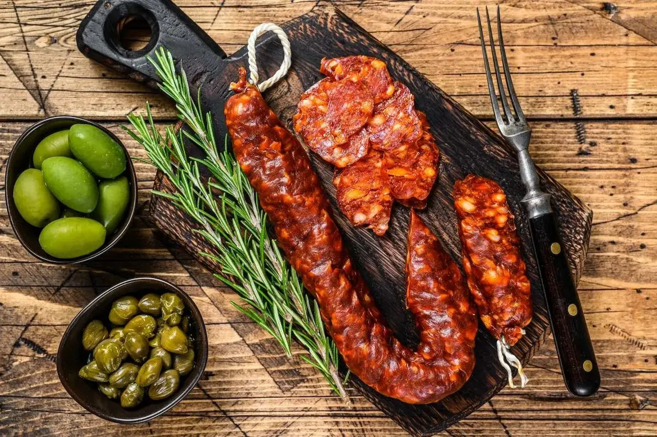 Chorizo co to? Pikantna kiełbasa, oliwki, kapary i rozmaryn na desce. Idealna przekąska.