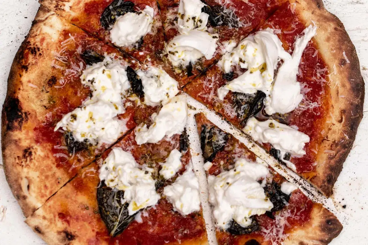 Pyszna pizza z burrata, polana oliwą i posypana parmezanem. Idealna na wspólne chwile.