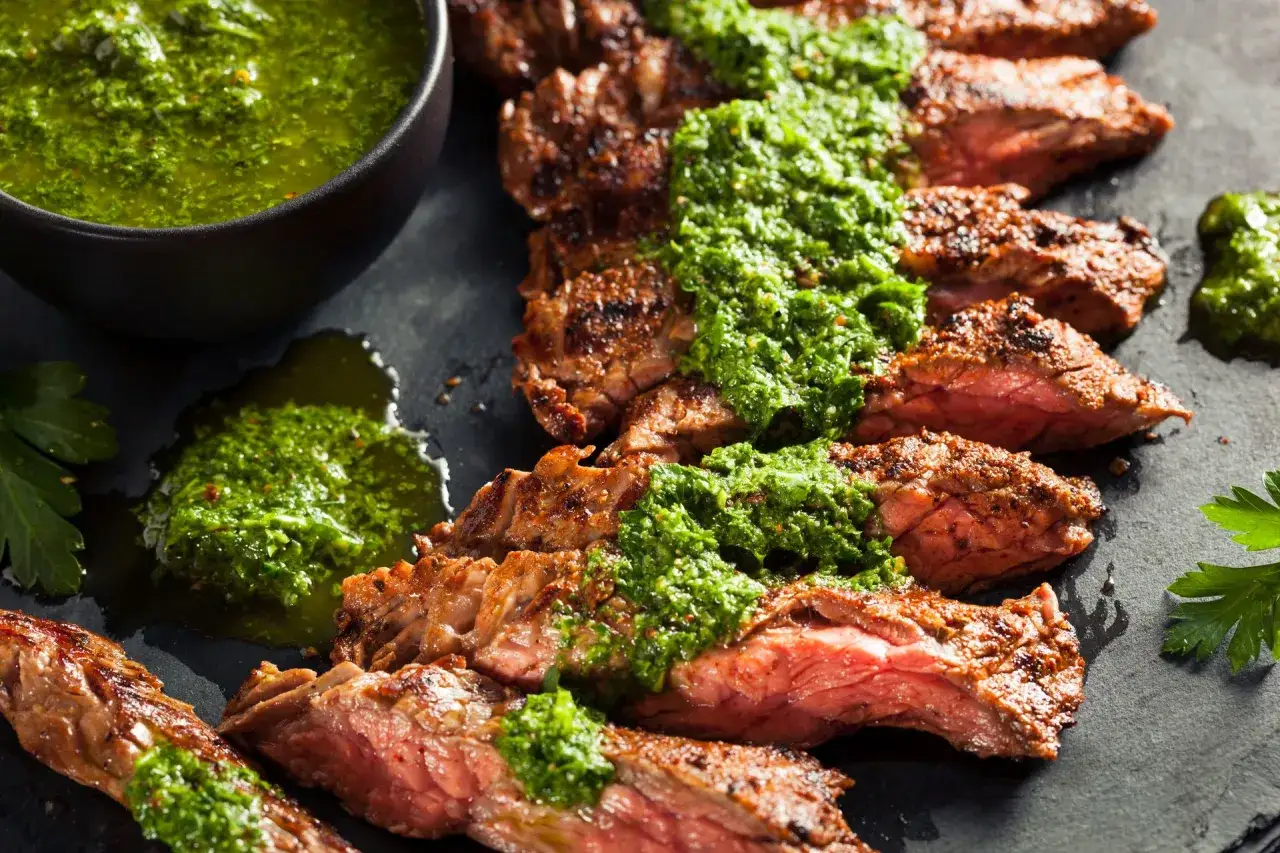 Pokrojony stek wołowy z aromatycznym, zielonym sosem chimichurri.