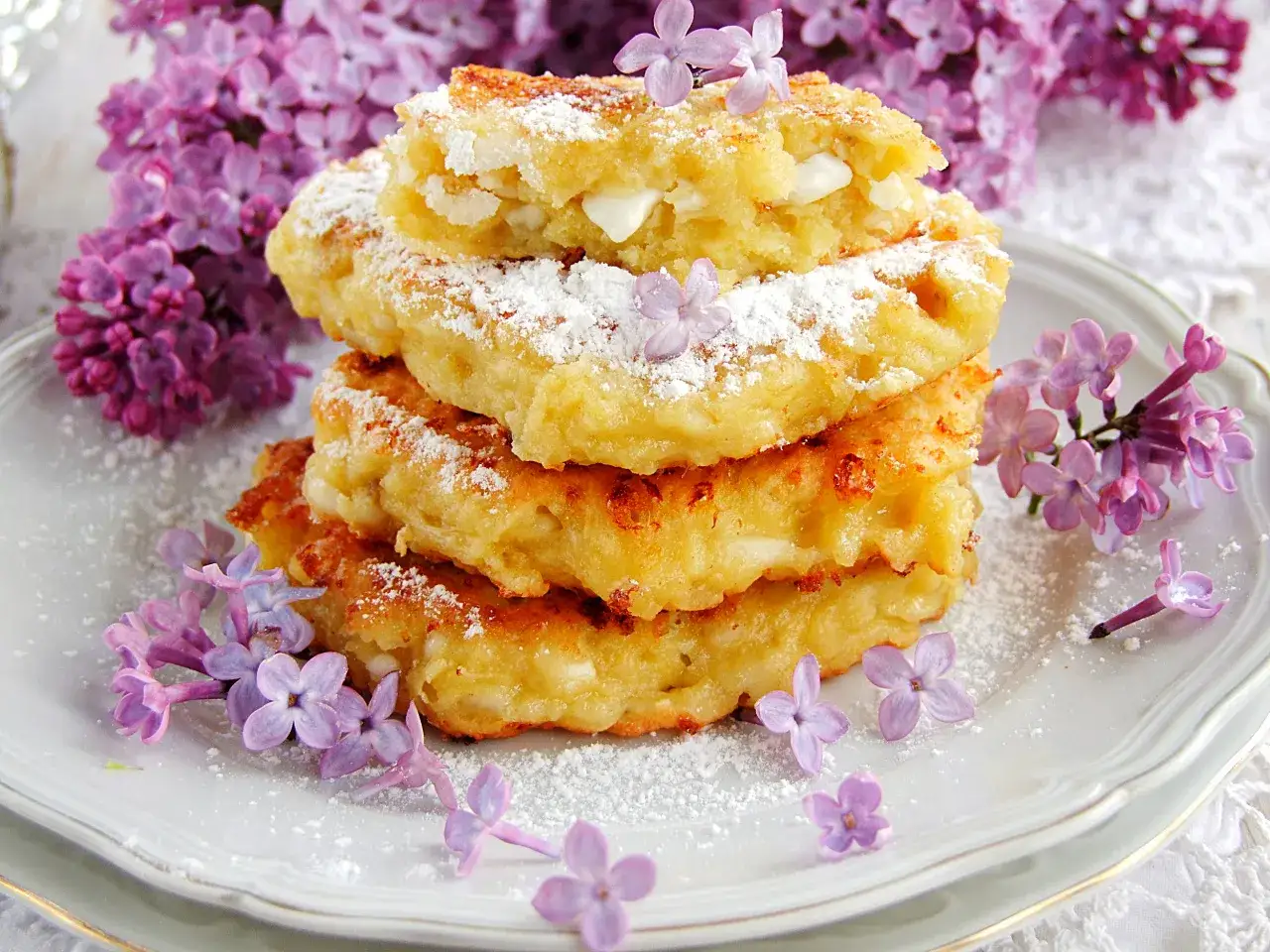 Fit placuszki z serka wiejskiego i banana, posypane cukrem pudrem, ozdobione kwitnącym bzem.