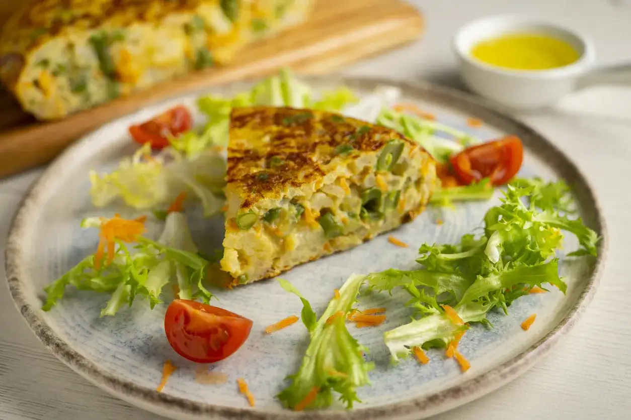 Pyszny omlet z piekarnika z warzywami, podany z sałatką i pomidorkami.